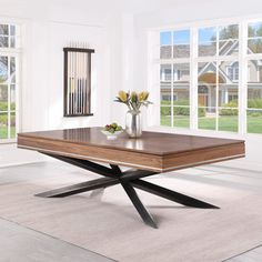 a wooden table with two vases and flowers on it in an empty room next to windows