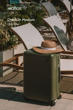 a woman sitting on a chair next to a piece of luggage with a straw hat on top