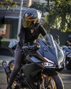 a person on a motorcycle wearing a helmet and black leather pants with gold trims