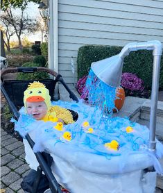 a baby in a stroller wearing a ducky hat