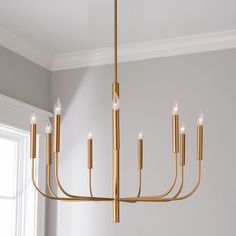 a gold chandelier hanging from the ceiling in a room with white walls and windows