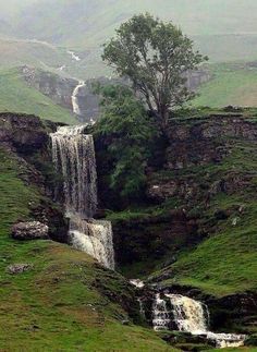 a small waterfall in the middle of a green valley