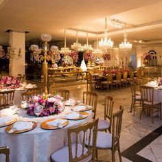 a banquet hall with tables and chairs set up for an event or function, decorated with chandeliers and floral centerpieces