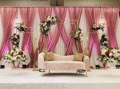 a couch sitting on top of a white floor next to a wall covered in pink drapes