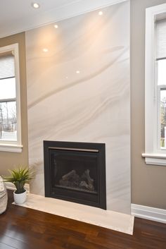 a living room with a fire place in the middle and two windows on either side