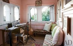 a living room filled with furniture next to a window and a guitar sitting on top of a table