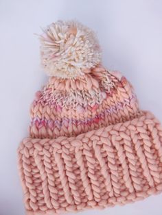 a pink knitted hat with a white pom - pom