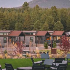 there are many tables and chairs in front of the building with mountains in the background