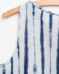 a blue and white striped dress hanging on a wooden hanger, with the fabric pulled back