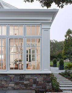 an image of a white house with lots of windows and furniture in the back ground