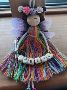 a colorful fairy doll sitting on top of a wooden table