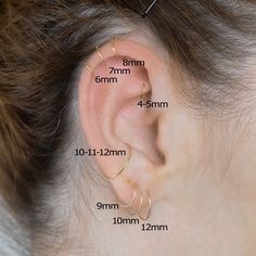 an ear with three different types of piercings on the side and two smaller ones behind it