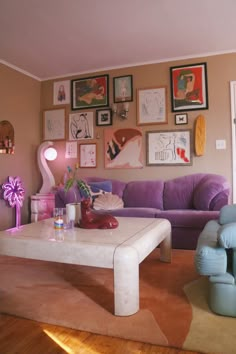 a living room filled with purple furniture and pictures on the wall above it's coffee table