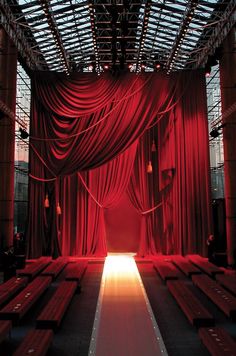 an empty stage with red curtains and benches