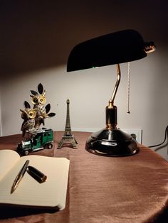 an open book sitting on top of a wooden table next to a lamp and statue