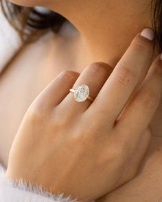 a woman's hand wearing a gold ring with a round diamond on the middle