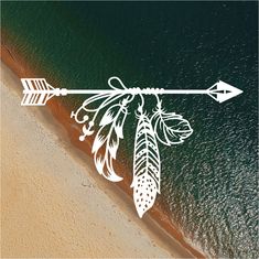 an arrow drawn on the side of a beach next to the ocean with flowers and leaves