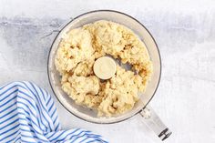 a food processor filled with dough on top of a blue and white striped towel next to it