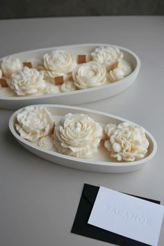 two white bowls filled with cupcakes sitting on top of a table next to a business card