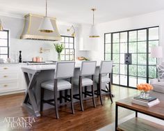 a kitchen with white cabinets and gray countertops next to a dining room table in front of a large window