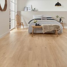 a bed room with a neatly made bed and wooden floors