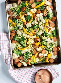 a casserole dish with sausage, broccoli and noodles in it on a table