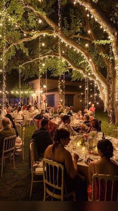 people are sitting at tables under trees with lights on them and the caption is in german