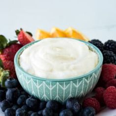 a bowl of yogurt surrounded by berries and oranges