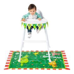 a little boy sitting in a high chair on top of a green and red rug