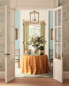 an open door leading to a dining room with a table covered in a yellow cloth