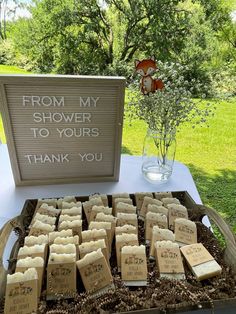 a table topped with lots of small wooden signs and flowers next to a sign that says, from my shower to yours thank you