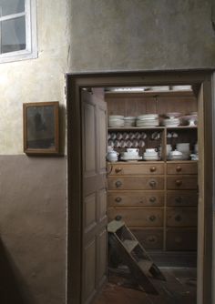 an open door leading into a room with lots of drawers and plates on the shelves