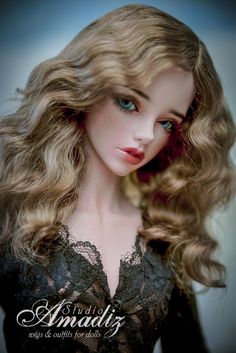 a doll with long blonde hair and blue eyes is posed for the camera, wearing a black dress