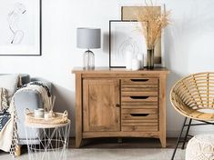 a wooden cabinet sitting next to a chair and table with pictures on the wall behind it