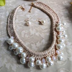 a necklace and earring set with pearls on a white tablecloth next to flowers