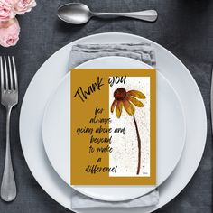 a white plate topped with a yellow flower next to a fork and knife