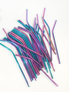 several different colored drinking straws on a white surface, one is blue and the other is pink