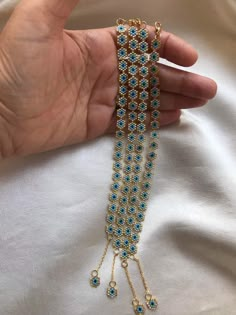 a person is holding some gold and blue beads in their hand, while they are wearing bracelets