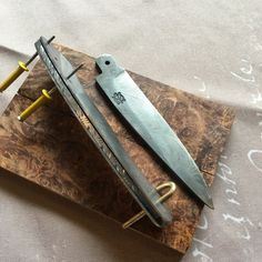 two knives are sitting on top of a piece of wood