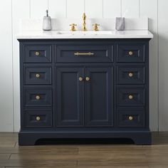 a dark blue bathroom vanity with two sinks and gold faucets on the top