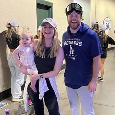 a man and woman standing next to each other holding a baby