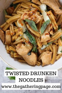 a white bowl filled with noodles and chicken on top of a marble counter next to a green leafy garnish