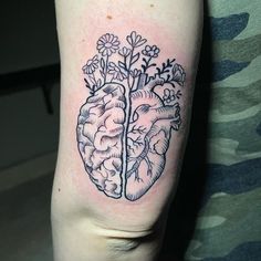 a person with a tattoo on their arm that has a heart and flowers in it