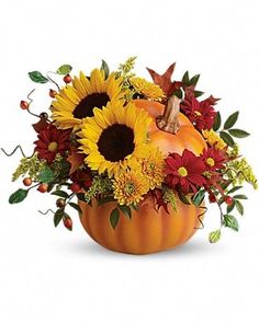 a pumpkin filled with sunflowers and other flowers