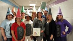 a group of people standing next to each other wearing party hats and holding chalkboards