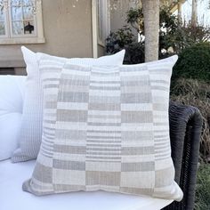 two pillows sitting on top of a white couch next to a tree in front of a house