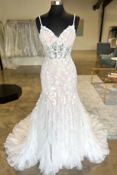 a white wedding dress on display in a room with other furniture and accessories behind it