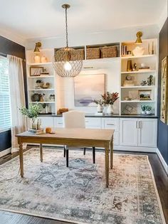 a dining room table and chairs in front of a window with open shelving on the wall