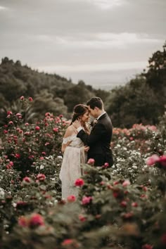 a bride and groom standing in a field of flowers