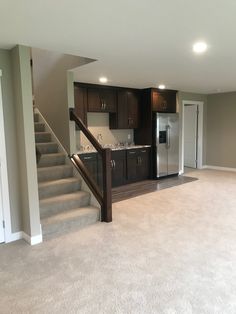 an empty living room with stairs leading up to the kitchen